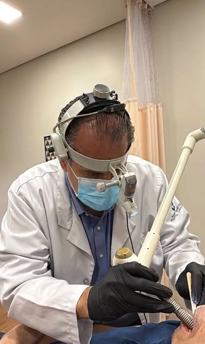 Dr. José Eduardo Marcondes, médico otorrinolaringologista, aplicando o laser Fotona na garganta de um paciente, no consultório
